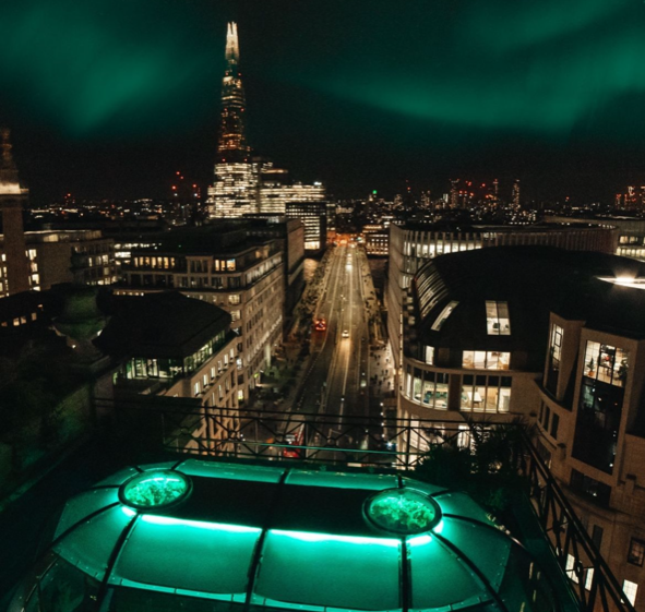 The Wagtail dining dome lit up in green overlooking London