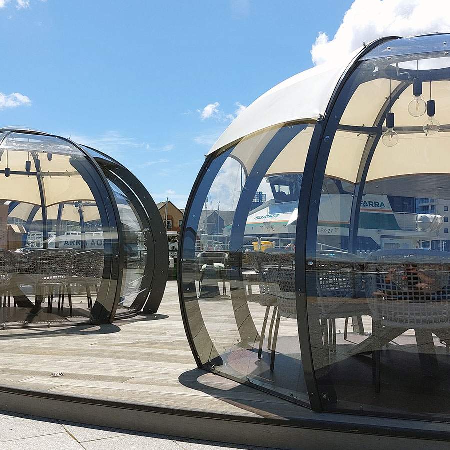 Dining pods at Southampton Harbour Hotel on a wooden deck with a blue sky 