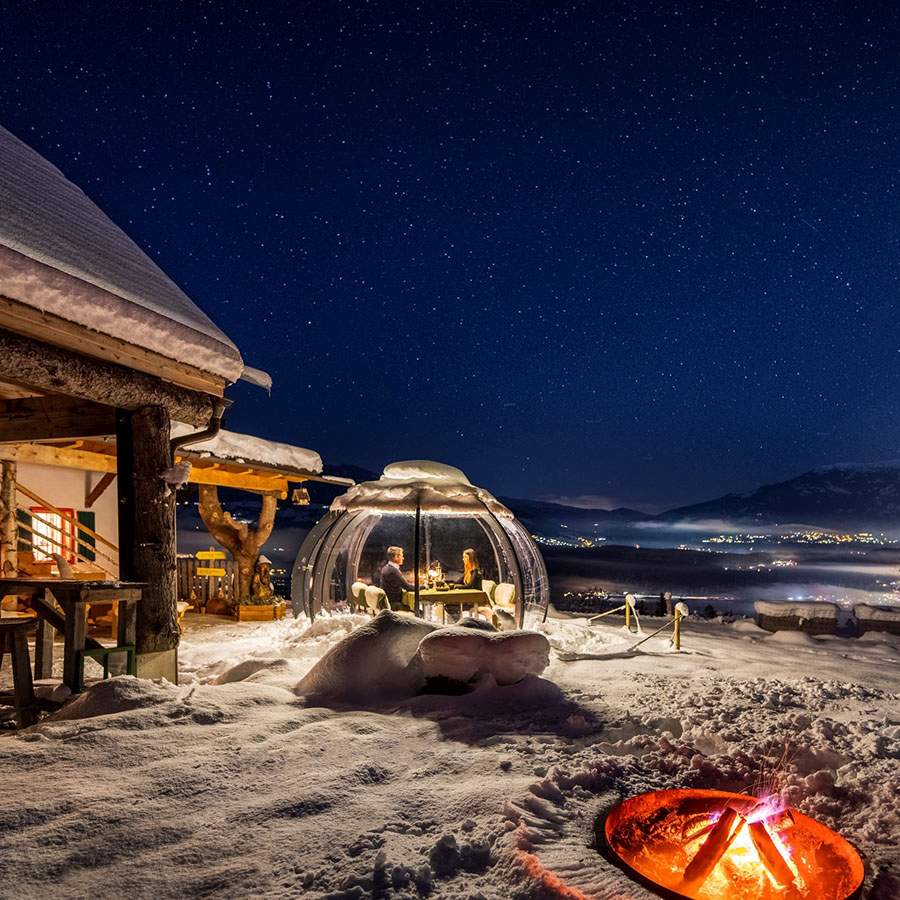 Stunning snow covered winter dining igloo in Austria with a romantic couple 