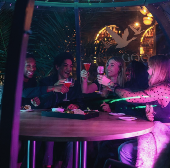Friends cheering inside a cosy dining pod
